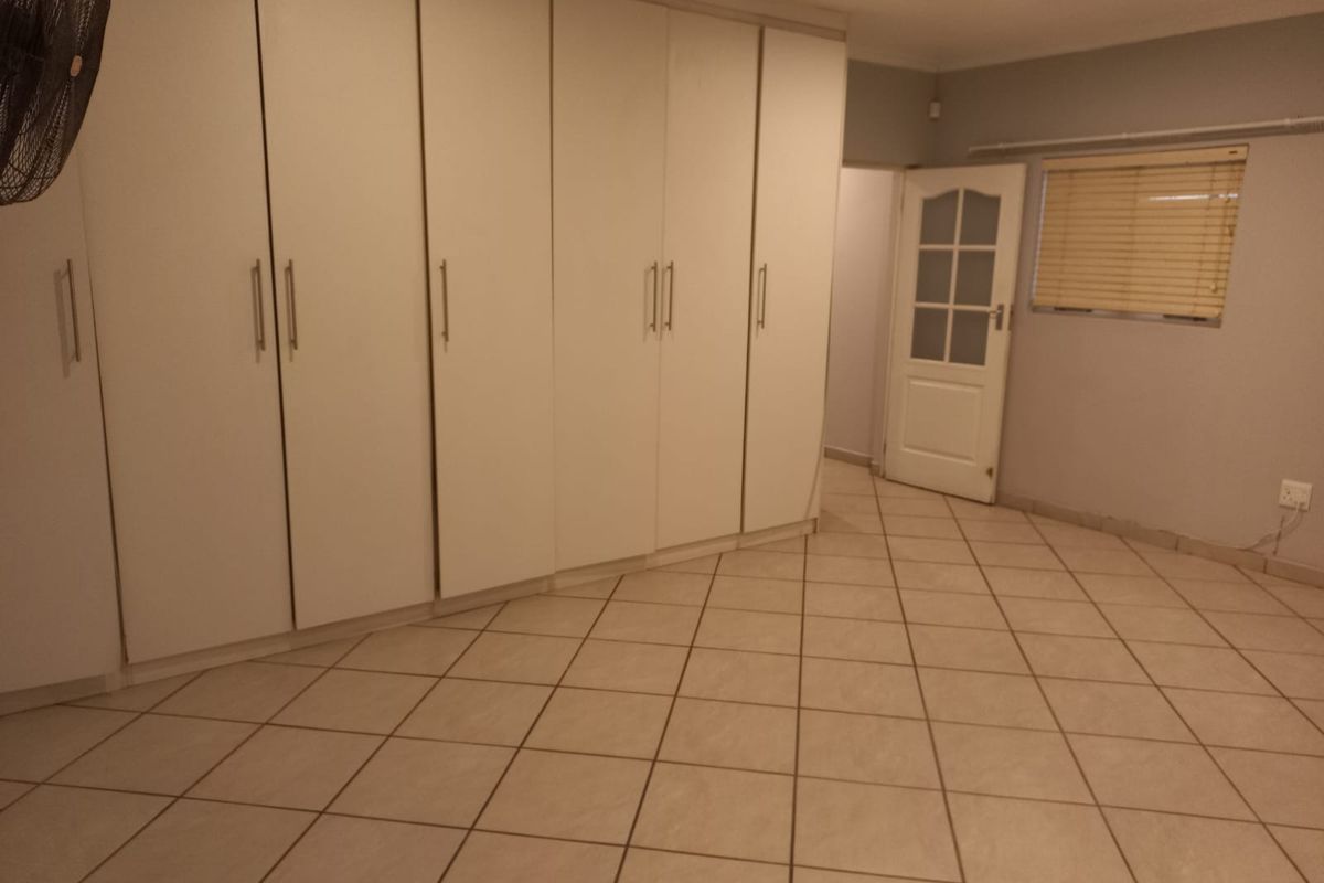 A bedroom featuring extensive built-in cabinetry, tiled flooring, and a classic panelled door with glass inserts.