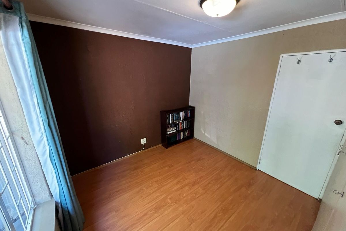 A bedroom featuring laminate flooring, a flush mount ceiling light, and dual-tone painted walls, presenting a blank canvas for potential interior updates.