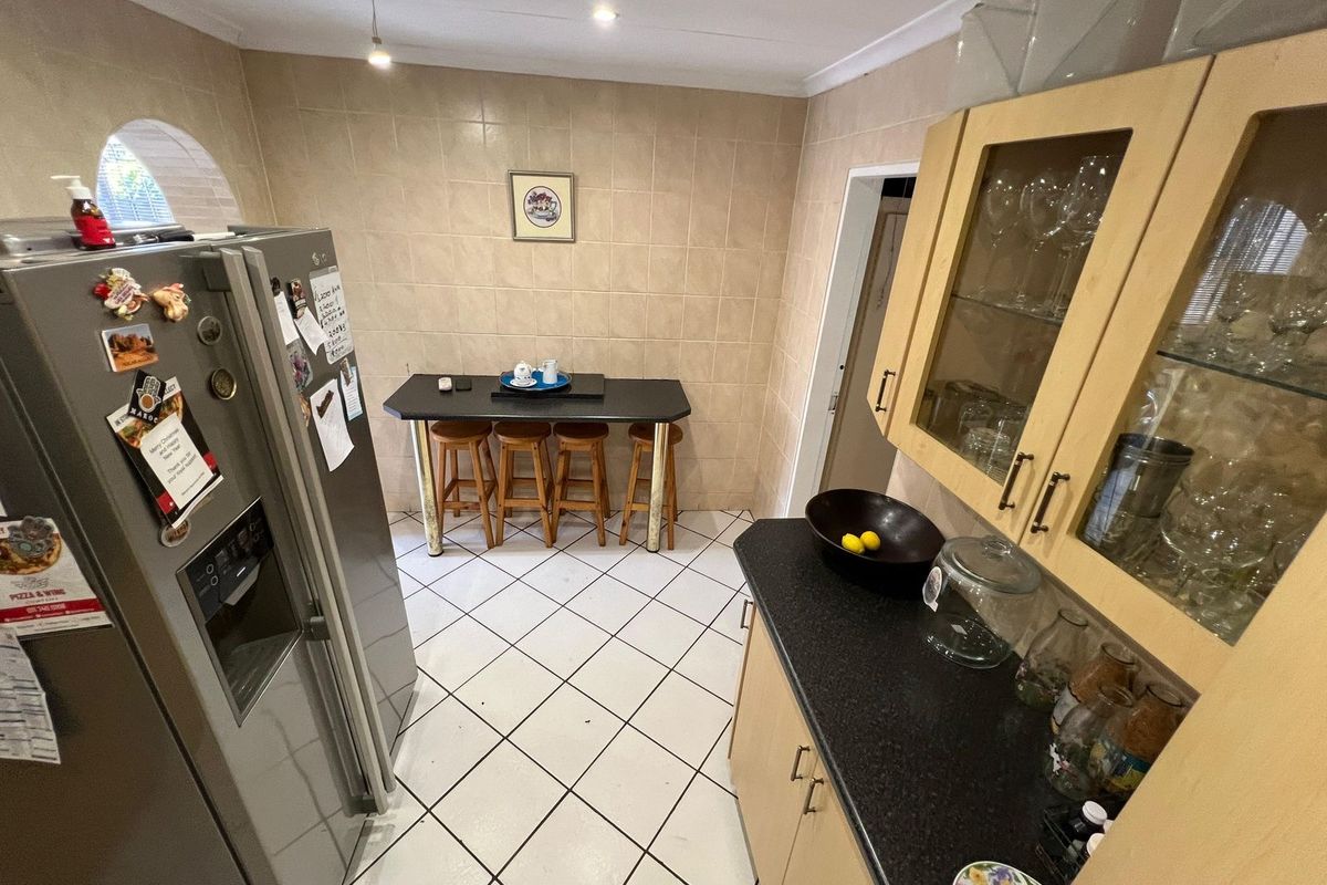 A functional kitchen area featuring tiled flooring, wall-to-wall tiling, built-in cabinetry with glass display sections, and dark laminate countertops.