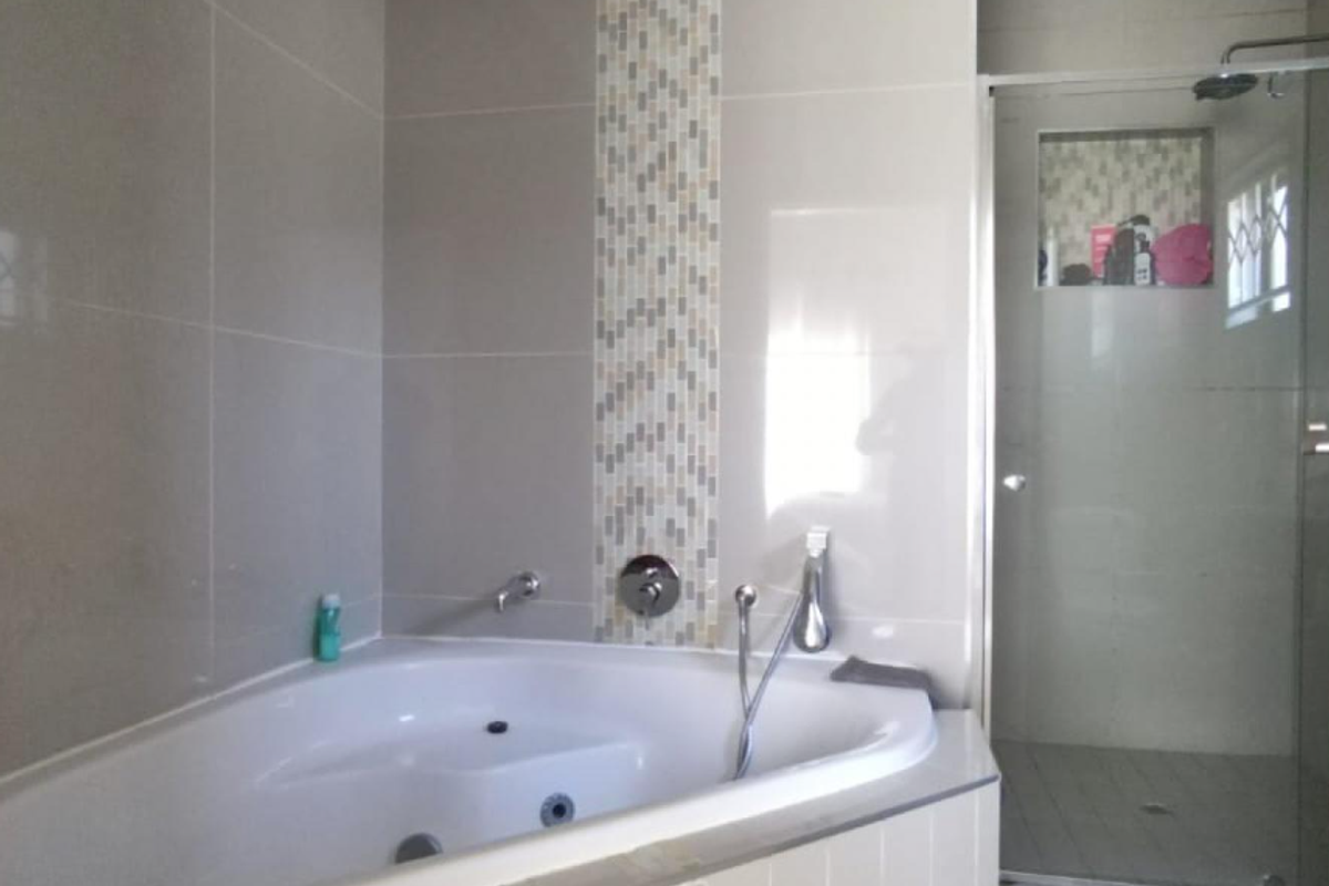 Modern bathroom featuring a corner spa bath with mosaic tile accents and a separate glass-enclosed shower with a built-in niche.