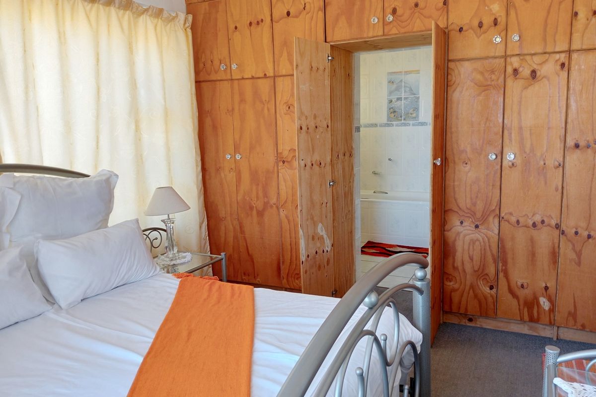 Bedroom featuring extensive built-in plywood cabinetry and direct access to an en-suite bathroom with a bathtub.