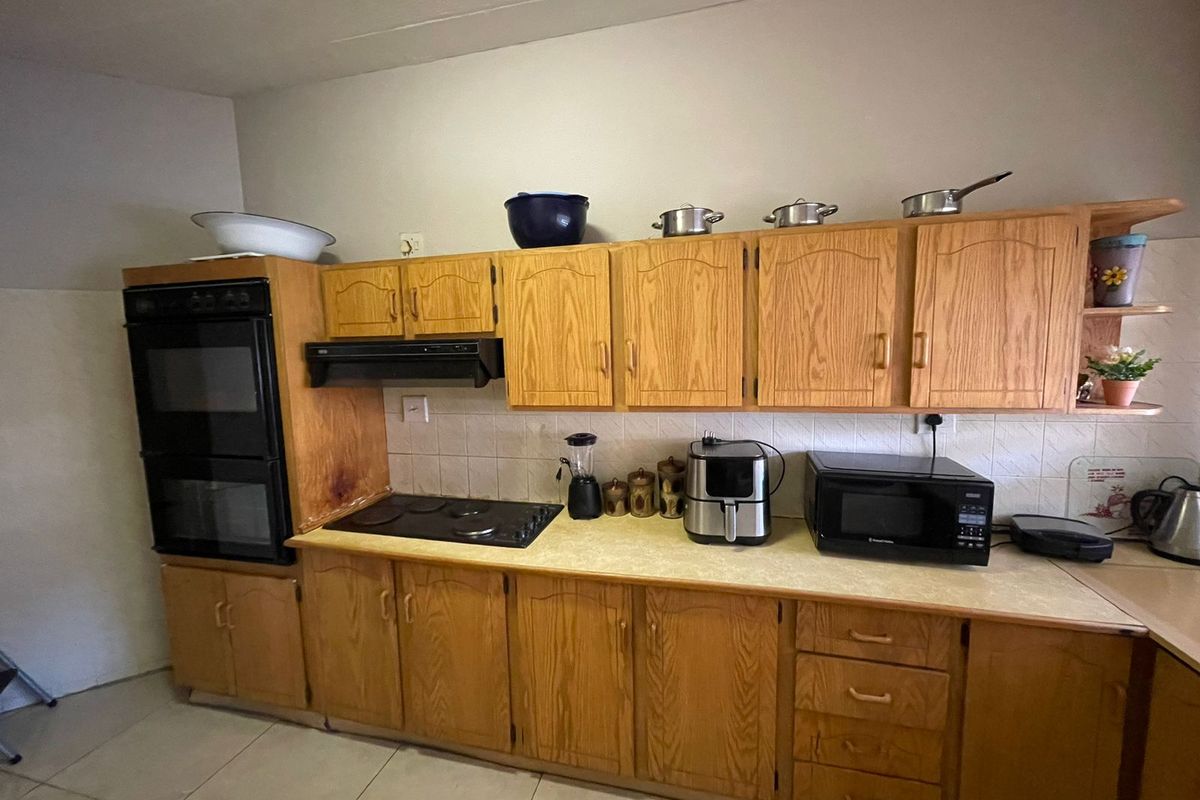 A functional kitchen featuring traditional wooden cabinetry, a built-in double oven, electric hob, and tiled backsplash, offering a classic layout with ample storage space.