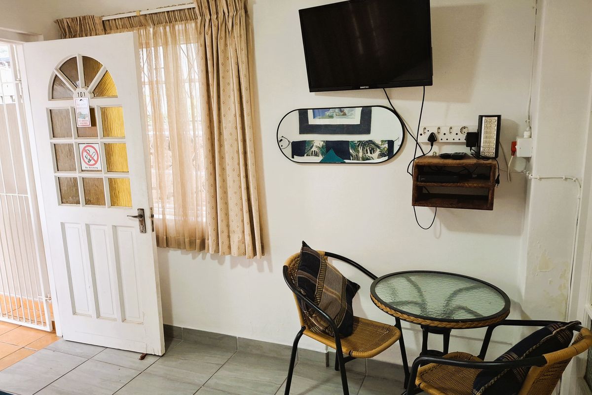 A functional living area featuring tiled flooring, a glass-paneled entry door, and wall-mounted television setup.