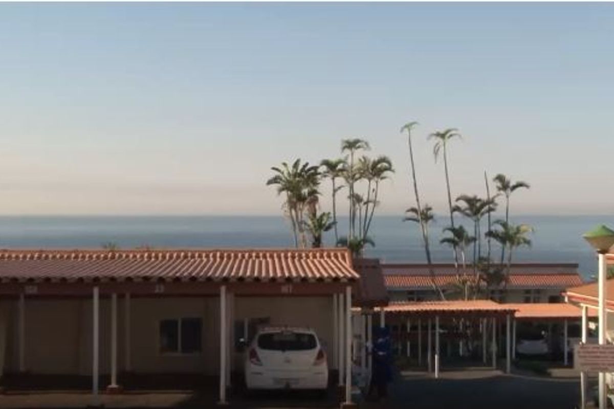 Exterior view of the apartment complex featuring covered parking bays and scenic ocean views in the background.