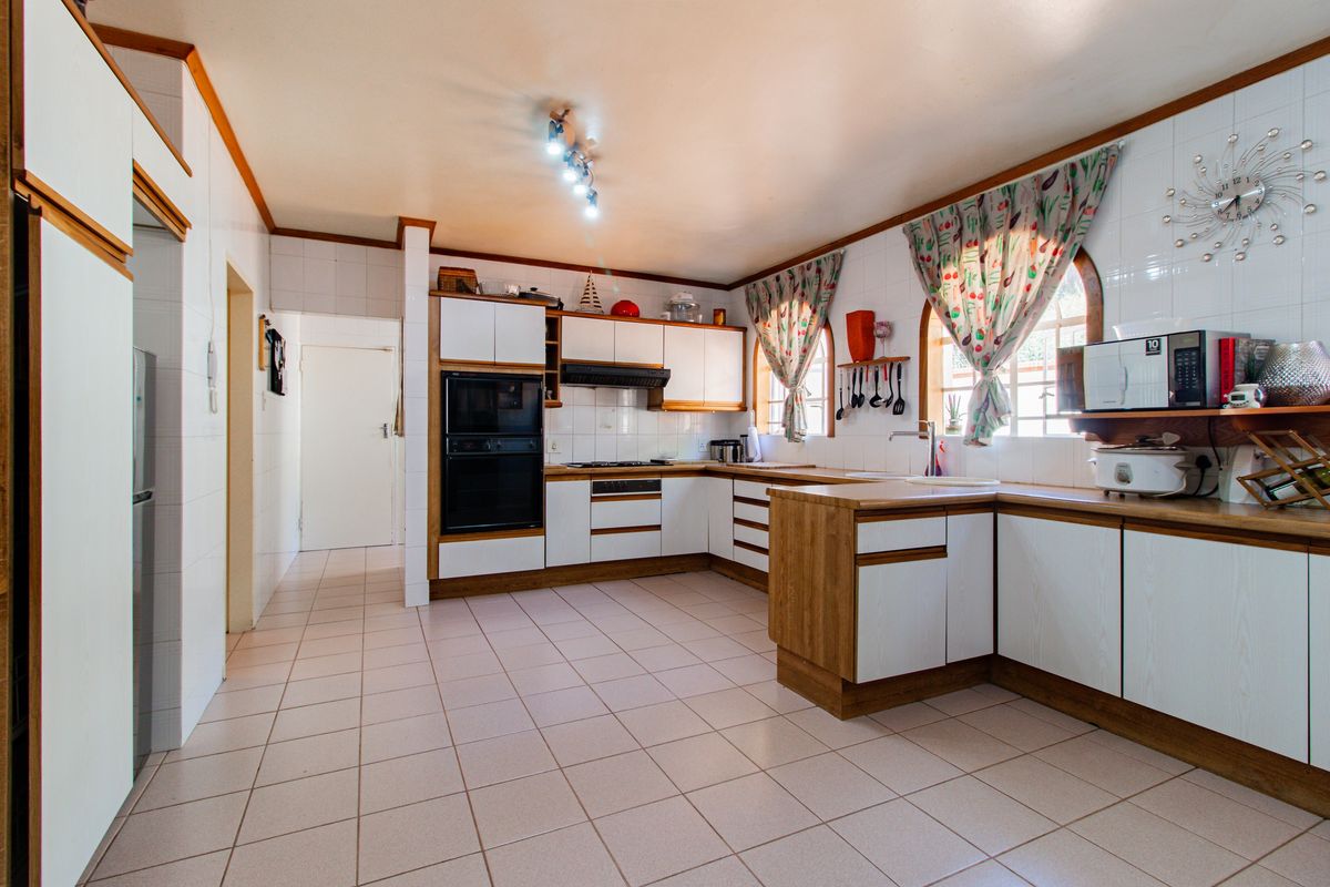 Spacious kitchen featuring built-in cabinetry, integrated oven, extractor fan, tiled flooring, and tiled walls, offering a functional layout with ample counter space.