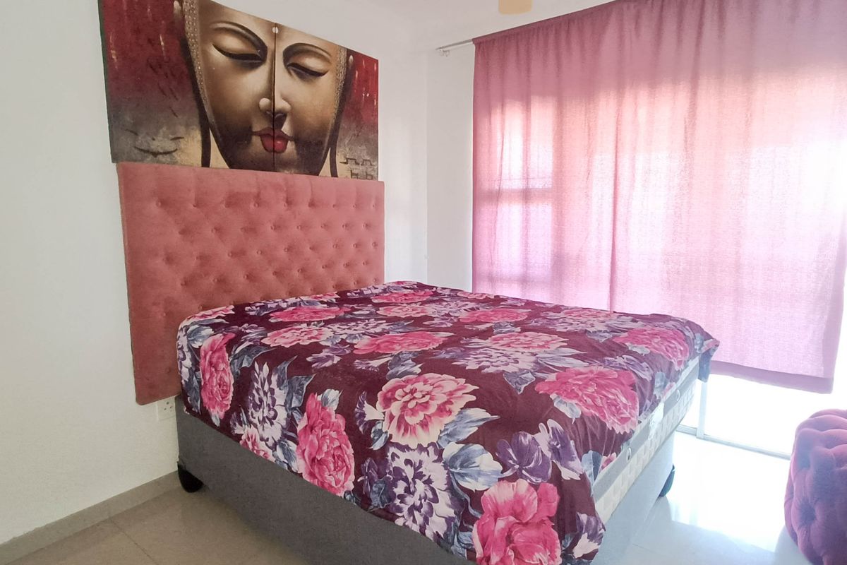 A bedroom featuring tiled flooring and large windows with curtains, providing natural light and access to the exterior.