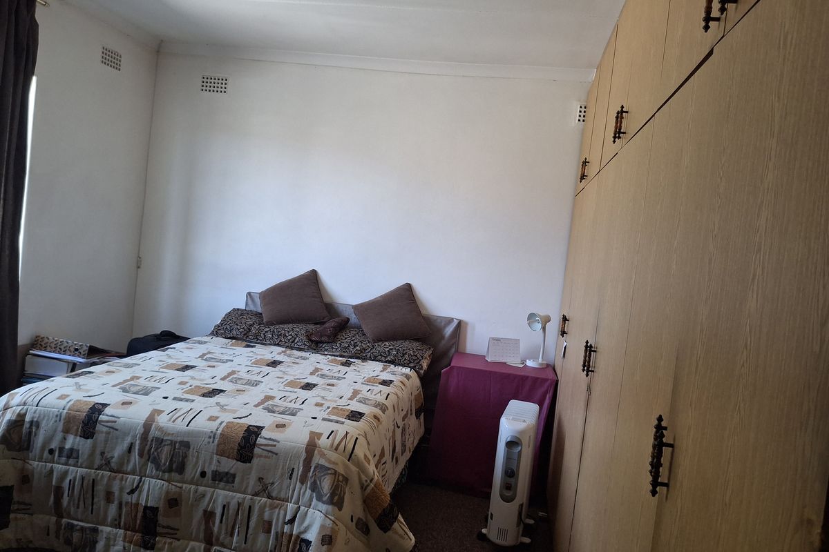 A bedroom featuring extensive built-in wooden cabinetry and carpeted flooring.