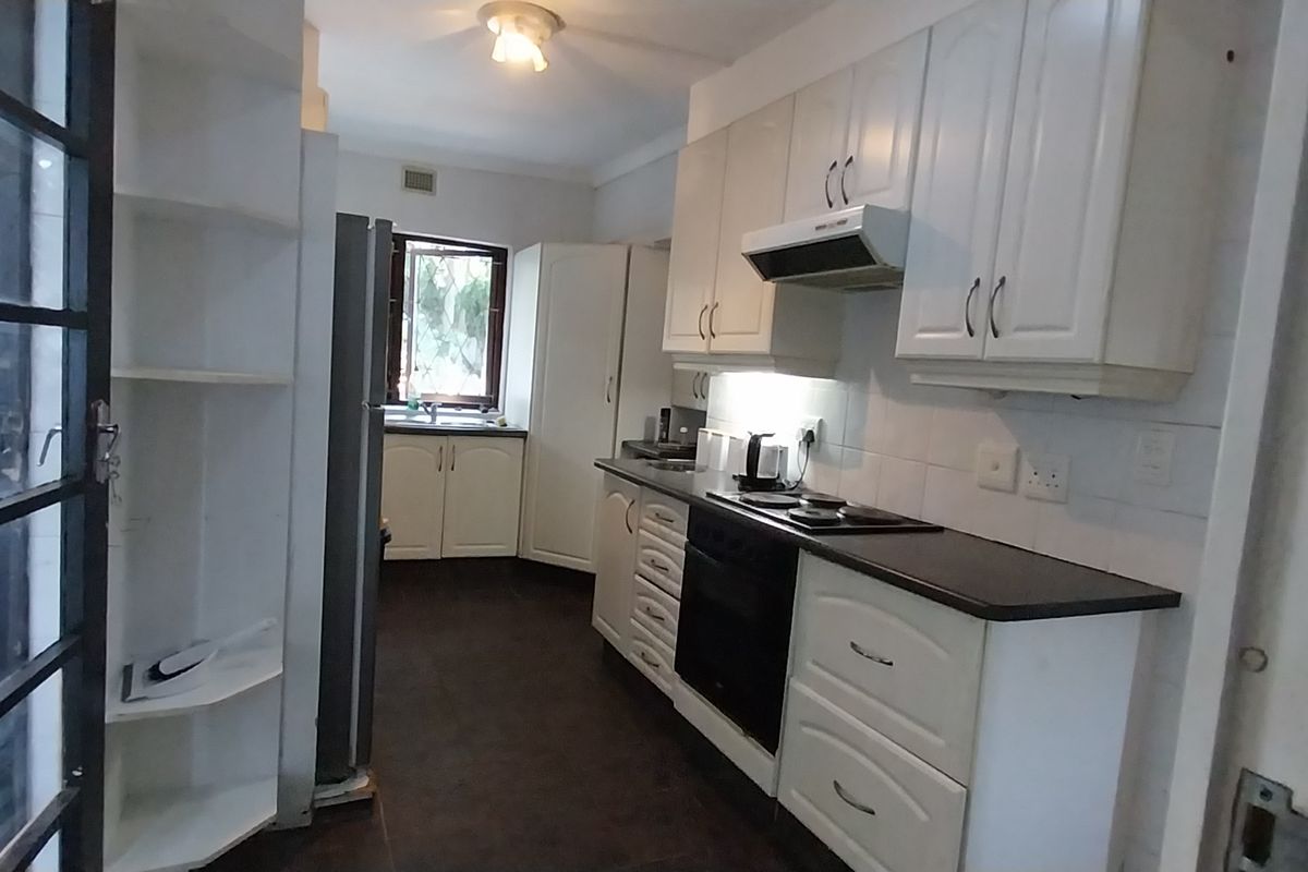 A functional kitchen featuring white cabinetry, dark countertops, built-in oven and hob, and a tiled backsplash, offering a clean and practical workspace.