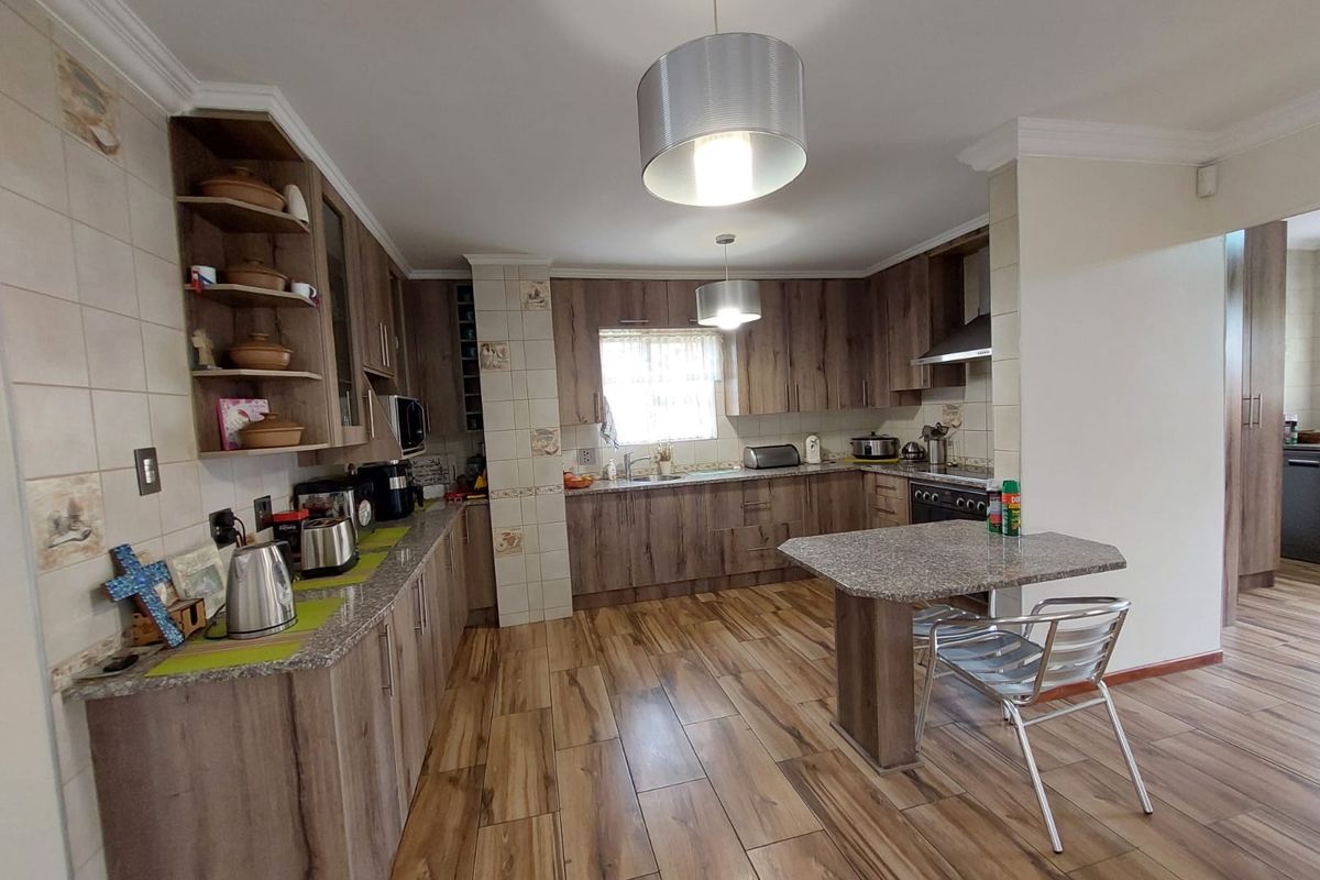 A functional kitchen featuring wood-look cabinetry, granite countertops, a built-in oven with extractor fan, and durable wood-look floor tiles.