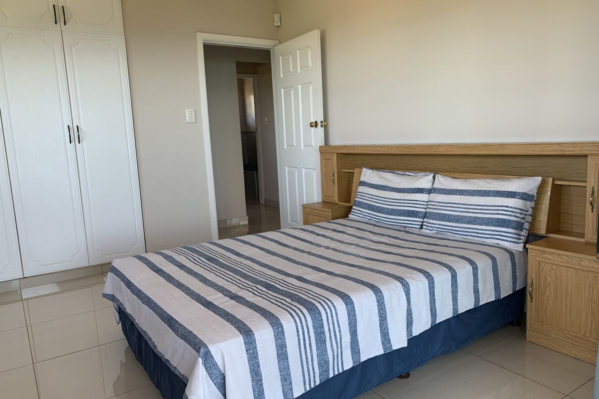 A well-maintained bedroom featuring built-in white cabinetry, tiled flooring, and a wooden headboard with integrated bedside storage.