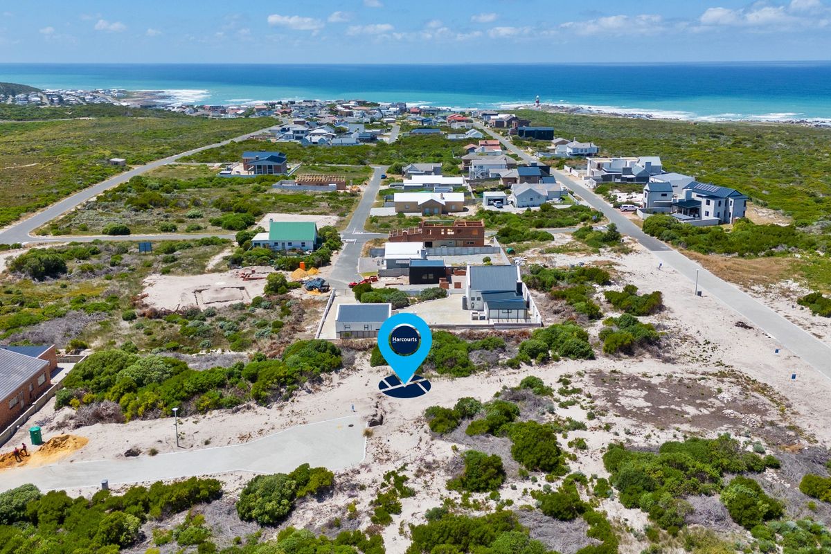 Aerial view of a coastal residential development featuring vacant land plots and established homes near the ocean.