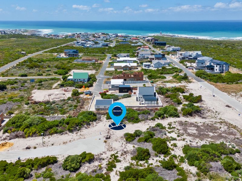Aerial view of a coastal residential development featuring vacant land plots and established homes near the ocean.
