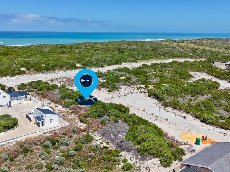 Aerial view of a vacant residential plot situated in a coastal estate, featuring natural vegetation and proximity to the ocean.