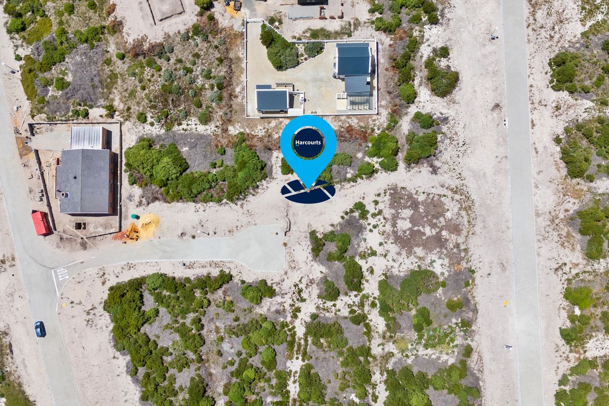 Aerial view of a vacant residential plot situated in a coastal development with established road access and surrounding natural vegetation.