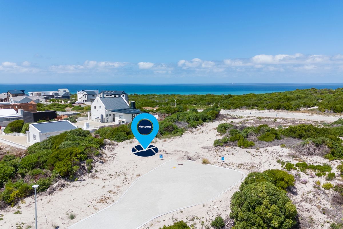 Aerial view of a vacant residential plot situated in a coastal estate, featuring natural vegetation and proximity to the ocean.