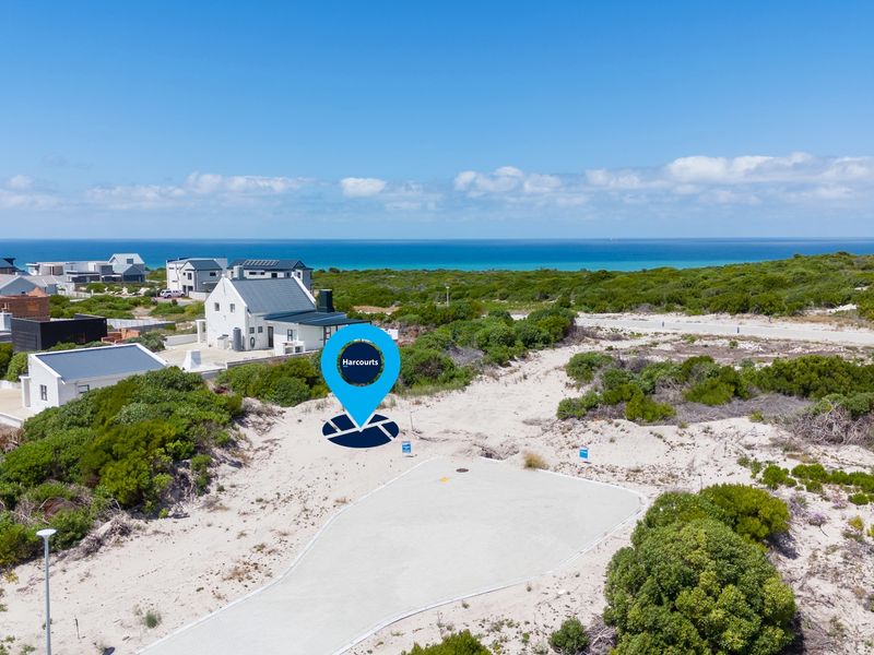 Aerial view of a vacant residential plot situated in a coastal estate, featuring natural vegetation and proximity to the ocean.