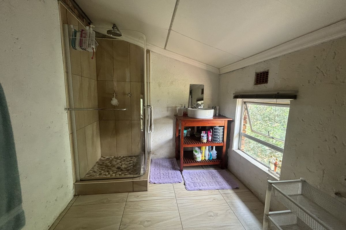 A compact bathroom featuring a glass-enclosed shower, vessel sink vanity, and tiled flooring, requiring cosmetic updates to the wall finishes.