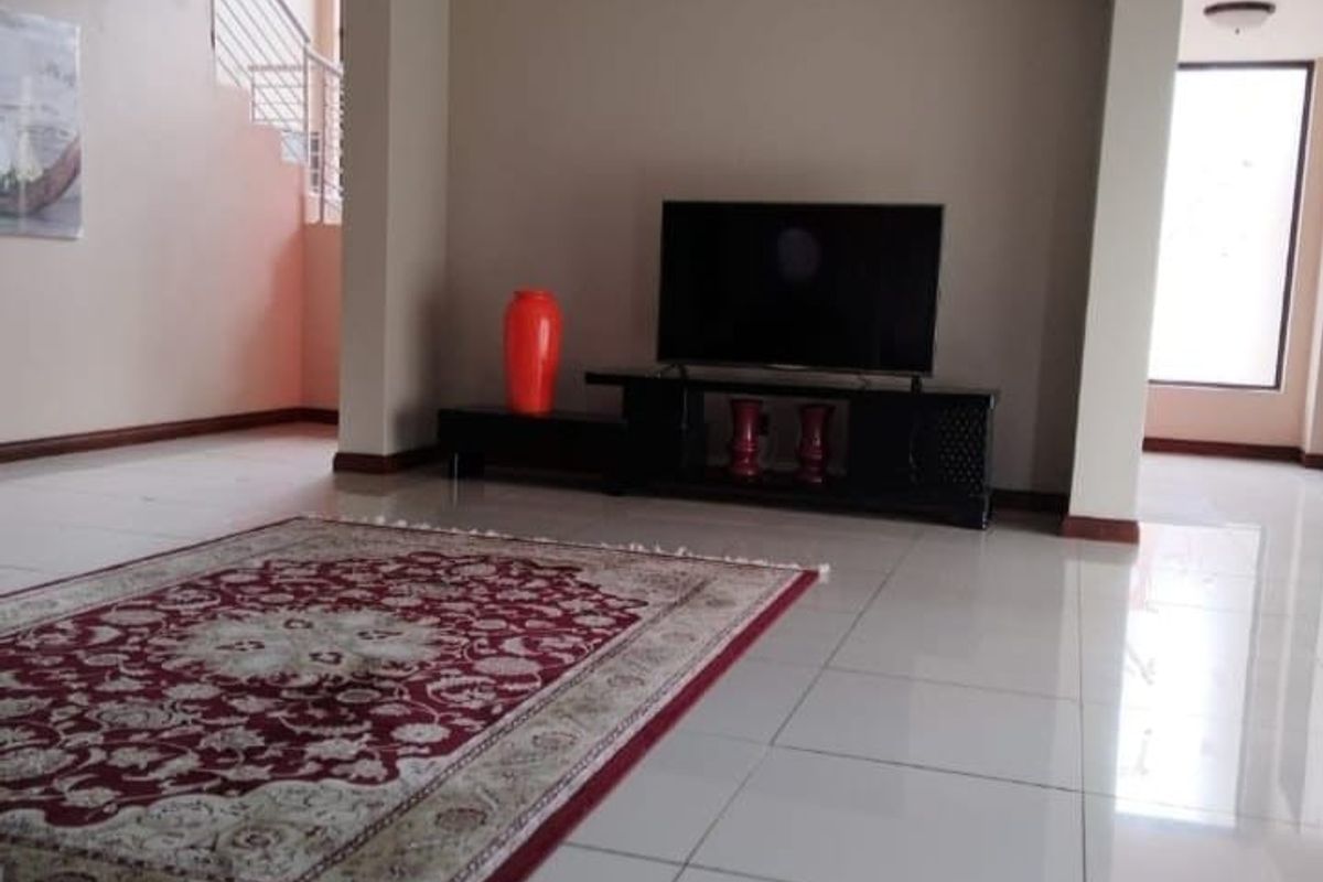 Spacious open-plan living area featuring tiled flooring, neutral wall tones, and a staircase leading to the upper level.