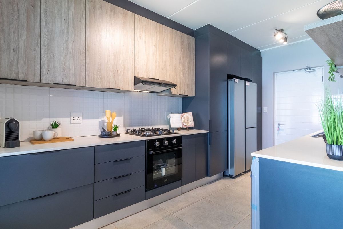 Modern kitchen featuring dark cabinetry, light wood-look upper cabinets, stone countertops, built-in gas hob, oven, and extractor fan.