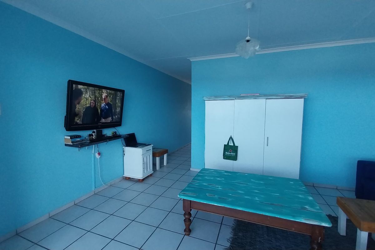 A living area featuring bright blue walls, tiled flooring, and a built-in wardrobe, offering a functional space with potential for cosmetic updates.