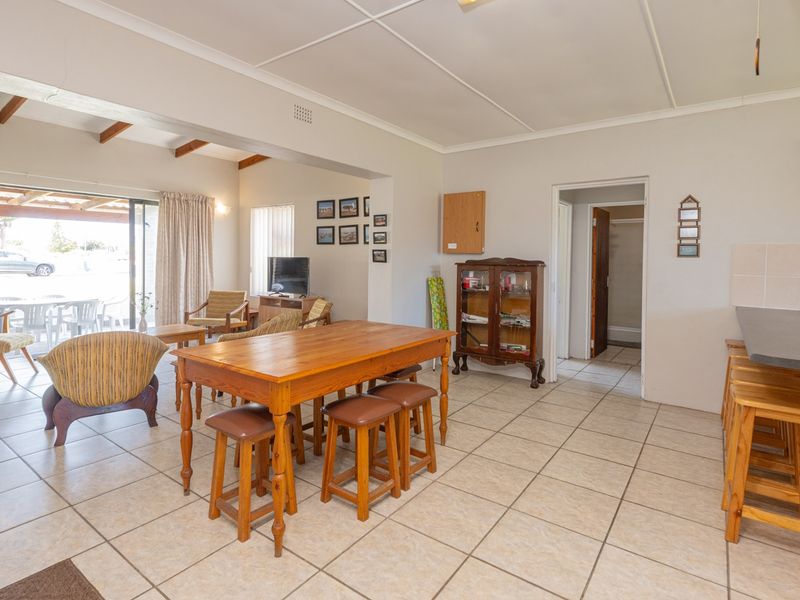 Spacious open-plan living and dining area featuring tiled flooring, exposed ceiling beams, and a breakfast bar connecting to the kitchen space.