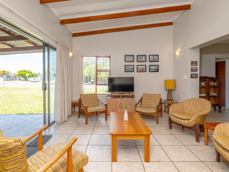 Open-plan living area featuring exposed timber ceiling beams, tiled flooring, and large sliding glass doors providing seamless access to the outdoor patio.