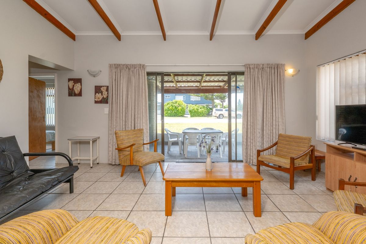 Spacious living room featuring exposed timber ceiling beams, ceramic floor tiles, and large sliding glass doors providing direct access to the outdoor patio area.