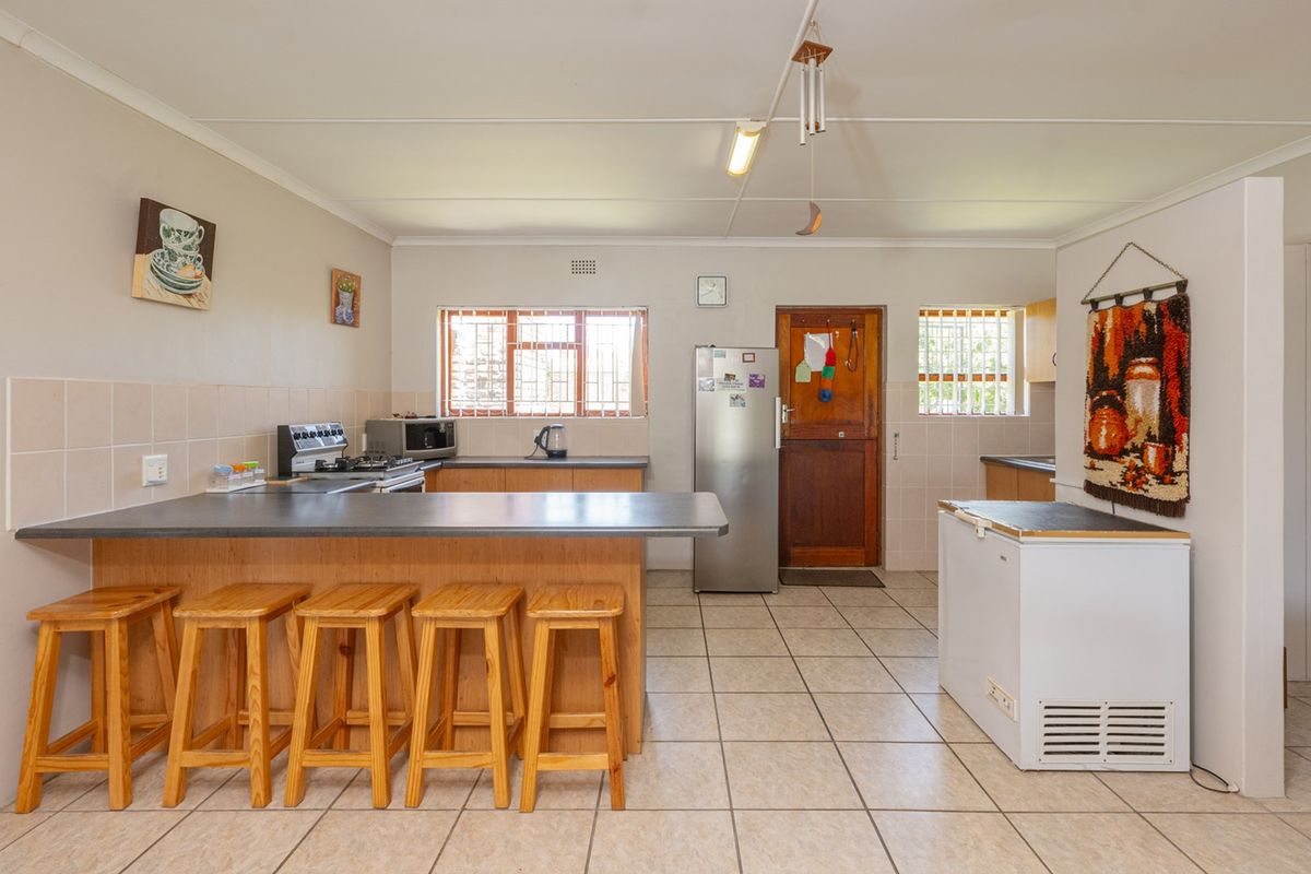 Functional kitchen featuring a breakfast bar, tiled flooring, ample cabinetry, and security-barred windows, offering a practical layout with potential for modern updates.