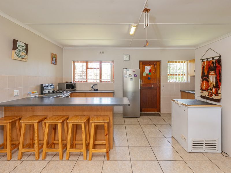 Functional kitchen featuring a breakfast bar, tiled flooring, ample cabinetry, and security-barred windows, offering a practical layout with potential for modern updates.