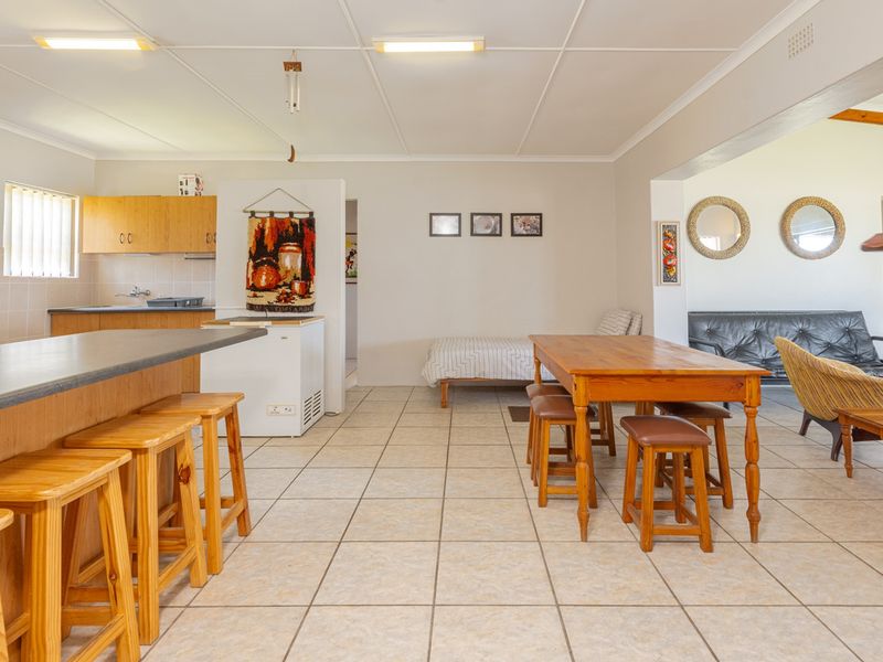 Spacious open-plan living area featuring a functional kitchen with breakfast bar, tiled flooring throughout, and integrated dining space.