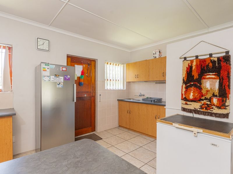 A functional kitchen featuring laminate cabinetry, tiled flooring, and a stainless steel sink, offering a practical layout with natural light from multiple windows.