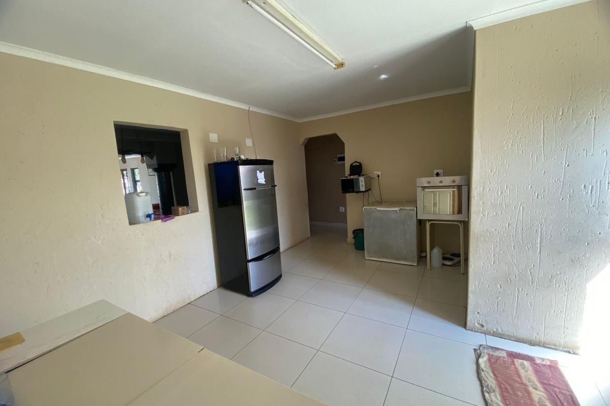 A basic kitchen area featuring tiled flooring, a pass-through window, and minimal fixed infrastructure, offering a blank canvas for renovation and cabinetry installation.