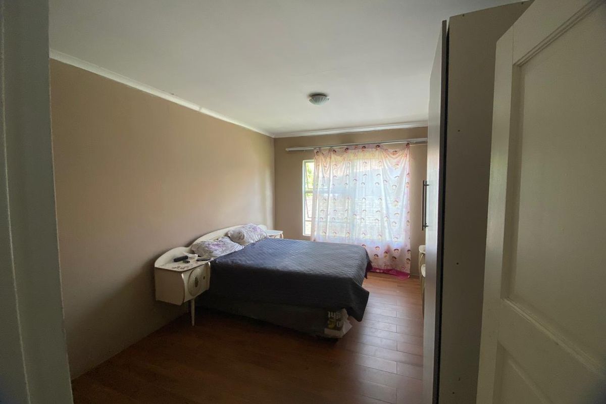 A standard bedroom featuring laminate flooring and a built-in cupboard, offering a functional space with neutral wall tones.