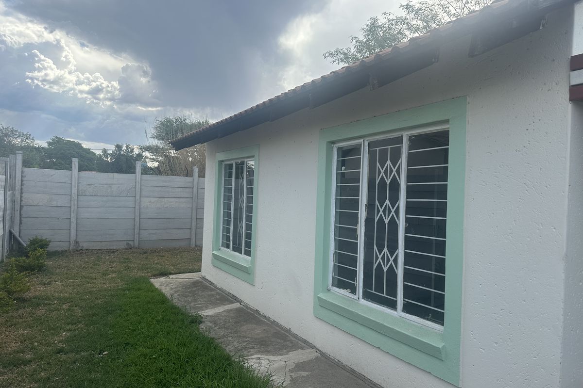 Rear exterior view of the house featuring a tiled roof, security bars on windows, and a precast concrete boundary wall.