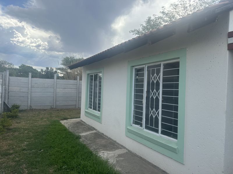 Rear exterior view of the house featuring a tiled roof, security bars on windows, and a precast concrete boundary wall.