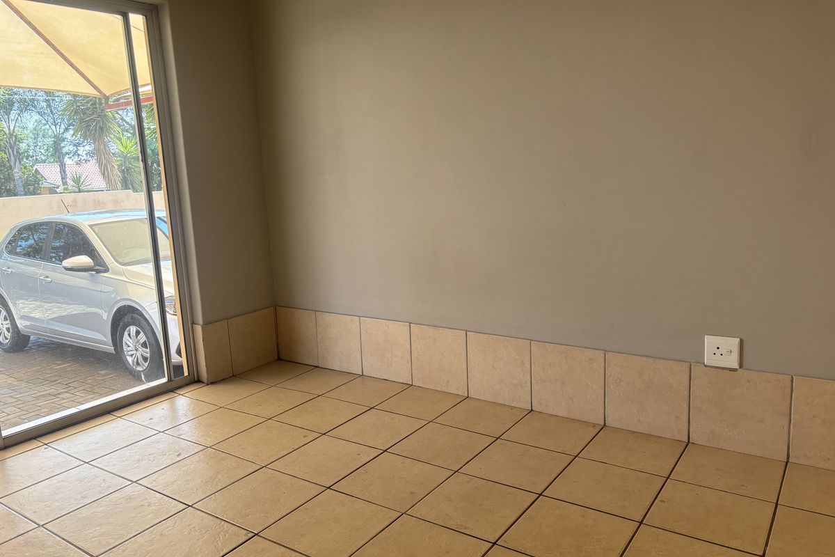 An empty room featuring tiled flooring, a low tiled wall skirting, and a sliding glass door providing access to the exterior.