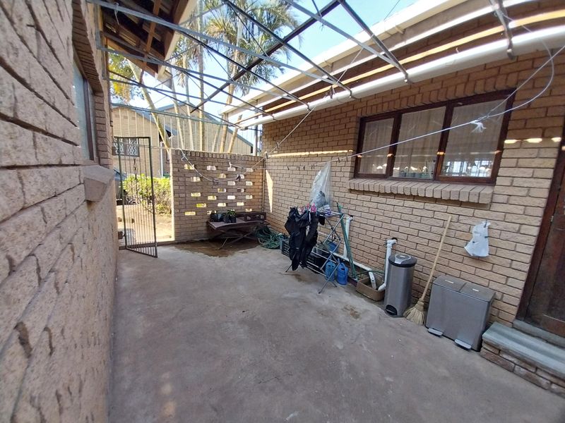 An outdoor utility and laundry area featuring brick walls, concrete flooring, and a metal frame structure, providing a functional space for household tasks.