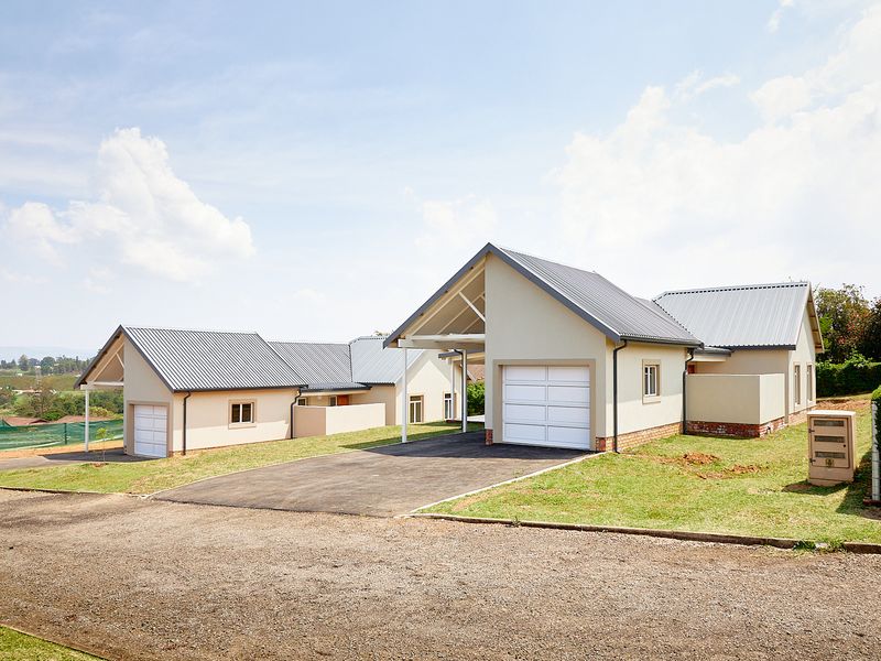 A view of the front exterior of the townhouse complex, featuring modern gabled roofs, white garage doors, and paved driveways.