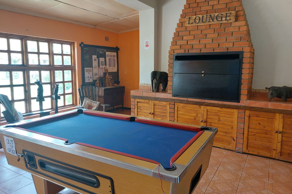 A communal lounge area featuring a large built-in brick fireplace, tiled flooring, and multi-pane windows.