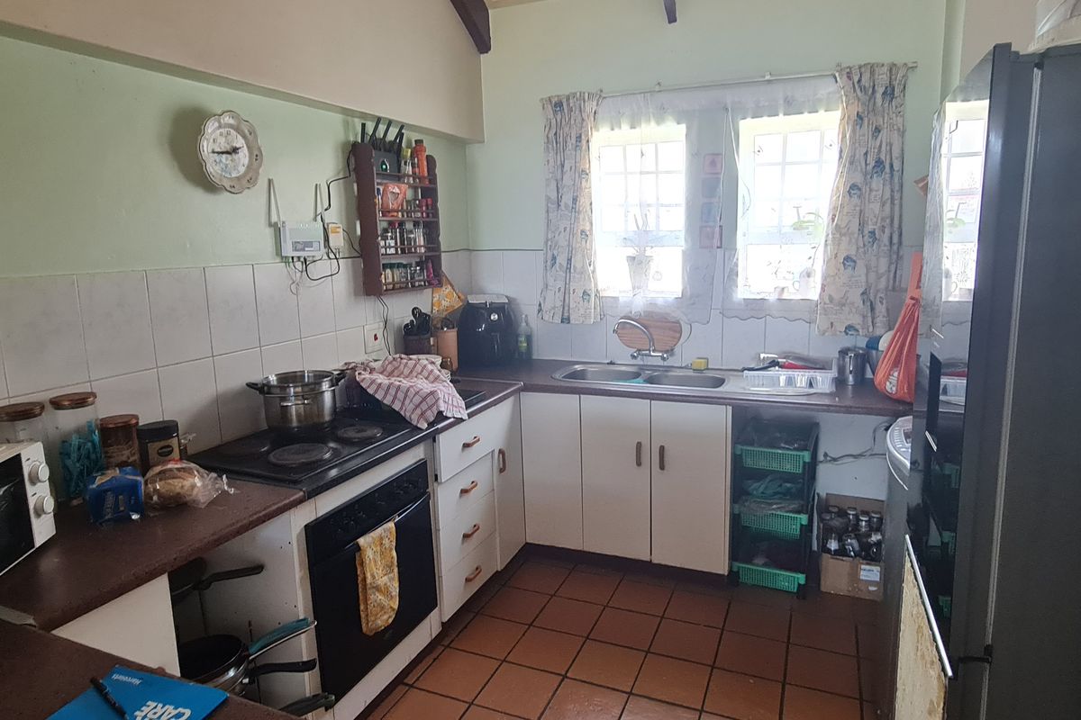 A functional kitchen featuring tiled flooring, a double basin sink, built-in cabinetry, and an integrated electric hob and oven.