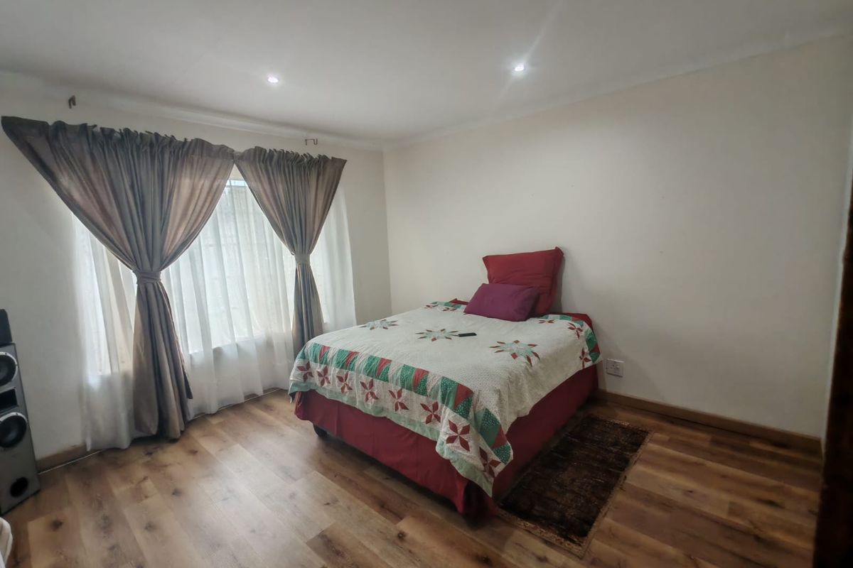 A bedroom featuring laminate flooring and recessed downlights, providing a neutral and functional space.