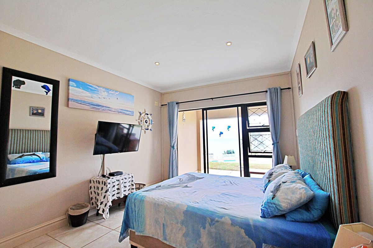 A well-lit bedroom featuring tiled flooring, recessed ceiling lighting, and sliding glass doors that provide direct access to an outdoor patio area.