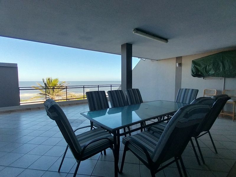 Spacious covered balcony featuring tiled flooring, a metal safety railing, and expansive ocean views, providing an ideal outdoor entertainment area.