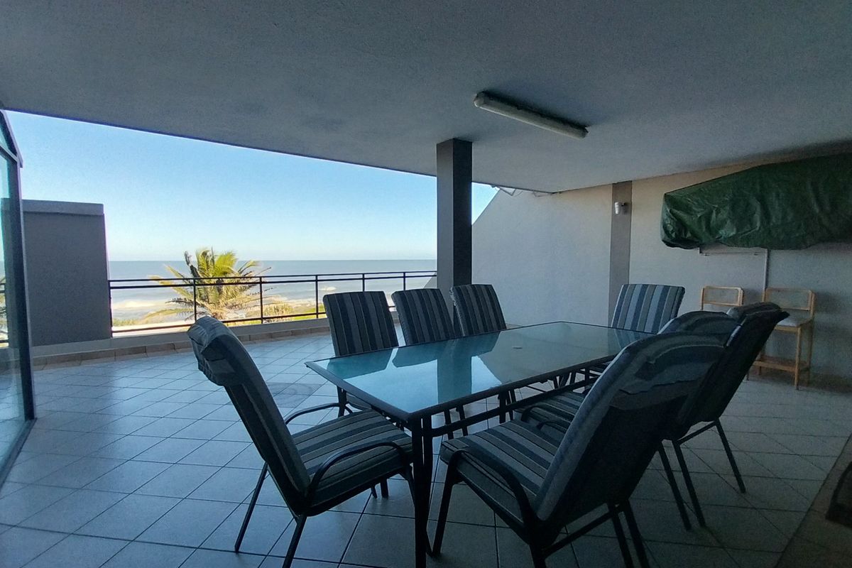Spacious covered balcony featuring tiled flooring, a metal safety railing, and expansive ocean views, providing an ideal outdoor entertainment area.