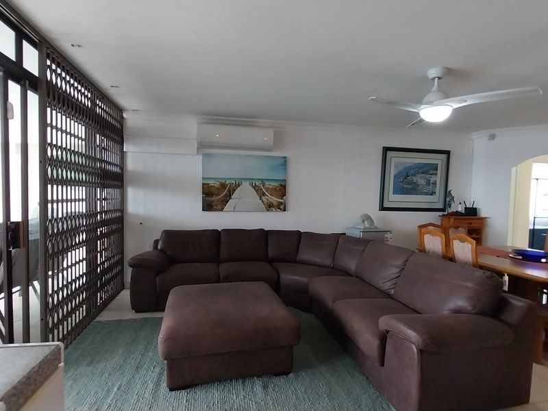 Open-plan living and dining area featuring tiled flooring, a ceiling fan, split-system air conditioning, and sliding glass doors leading to an outdoor space.