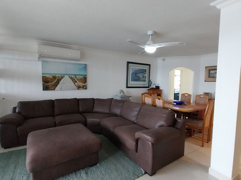 Spacious open-plan living and dining area featuring tiled flooring, a ceiling fan, and a wall-mounted air conditioning unit.