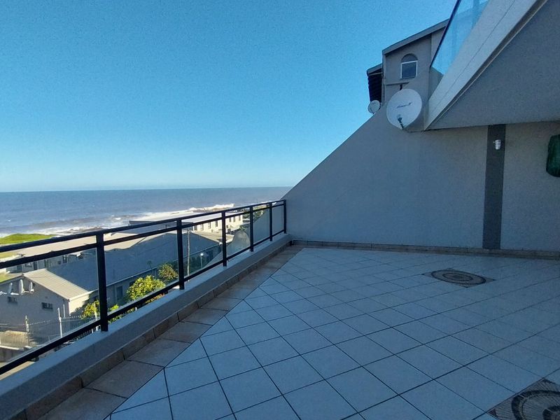 Spacious open-air balcony featuring tiled flooring, a glass balustrade, and expansive ocean views.
