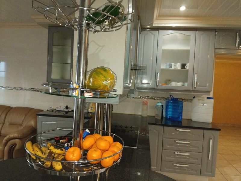 A functional kitchen featuring grey built-in cabinetry, dark granite countertops, and glass-fronted display cabinets with recessed ceiling lighting.