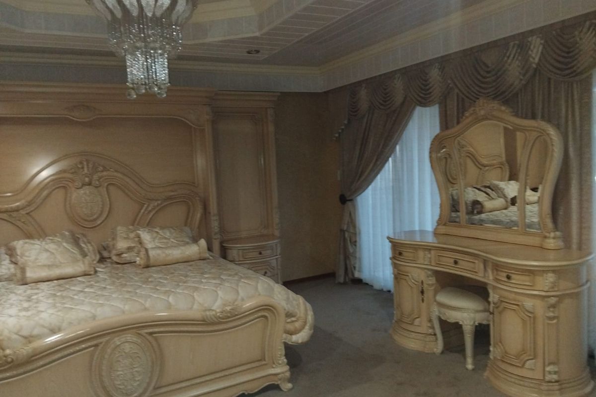 Spacious bedroom featuring a decorative tray ceiling with recessed lighting and a central crystal chandelier.