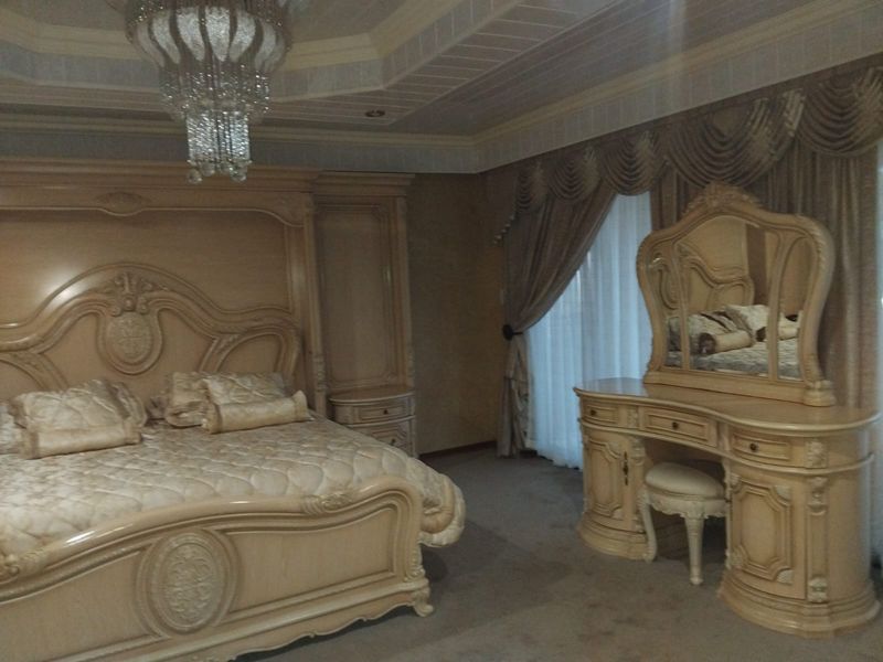 Spacious bedroom featuring a decorative tray ceiling with recessed lighting and a central crystal chandelier.